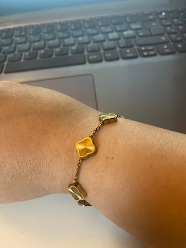 Customer wearing the gold Celine Clover Bracelet with textured gold motifs on their wrist.