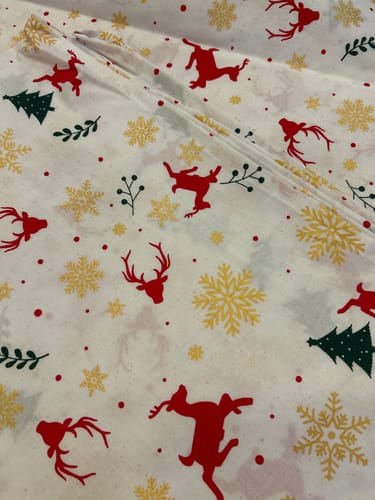Customer's close-up of the Festive Reindeer fabric, showing its pattern of red reindeer, green trees, and glittery snowflakes.