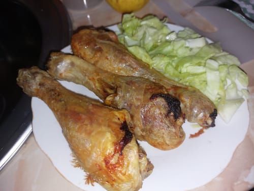 Clientul prezintă pulpele de pui gătite cu friteuza Air Fryer Novio StonePro, servite pe o farfurie cu salată.