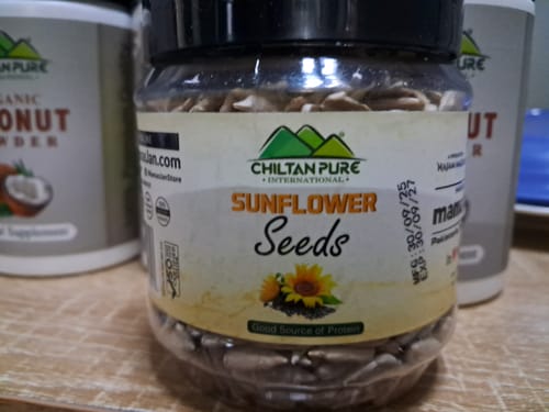 Customer's clear jar of Chiltan Pure Sunflower Seeds sitting on a wooden surface.