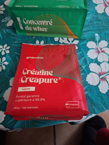 Client montrant son sachet rouge de Créatine Creapure® à côté d'un sachet de concentré de whey.