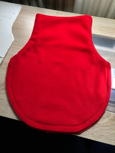 Customer's homemade red neck gaiter, sewn from the polar fleece fabric and laid on a wooden table.