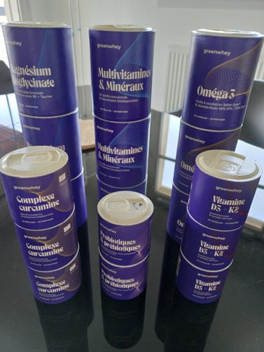 Photo d'un client montrant plusieurs pots de la marque, y compris le Magnésium Bisglycinate, sur une table.