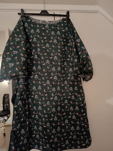 Reviewer's fun Christmas dress made from the Skiing Christmas Penguins fabric hanging on a hanger.