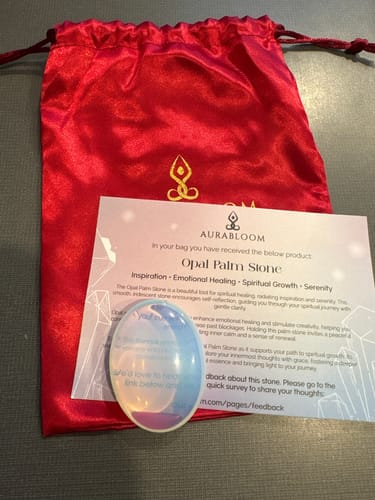 Customer's iridescent Opal Palm Stone from their monthly crystal subscription, with its red pouch and info card.