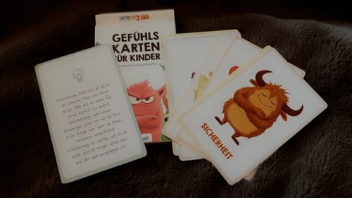 Ein Kunde zeigt die Edubini Gefühlskarten für Kinder, die mit der Schachtel und den illustrierten Karten ausgelegt sind.