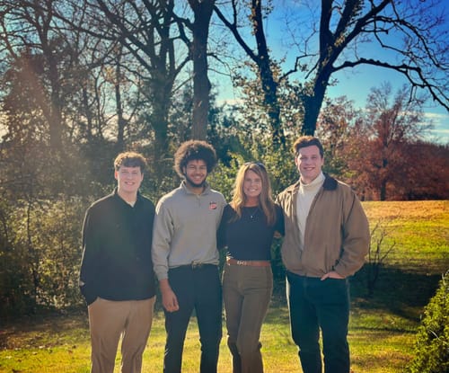Reviewer standing outdoors with three people, wearing the olive Strike A Cord wide leg jeans.