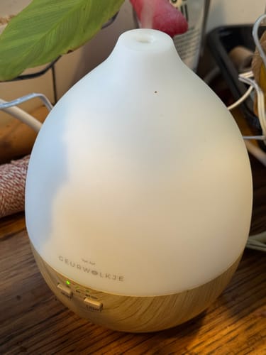 De ingeschakelde Nimbus 2.0 diffuser van een recensent, met een verlichte witte bovenkant en houten basis.