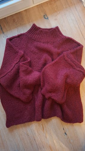 Kunde zeigt den weinroten, übergroßen CasualCozy Pullover mit Stehkragen.