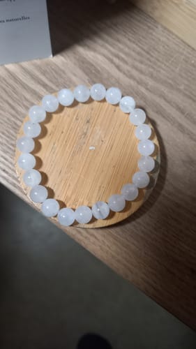Photo d'un client du bracelet en pierre de lune, posé en cercle sur une surface en bois.