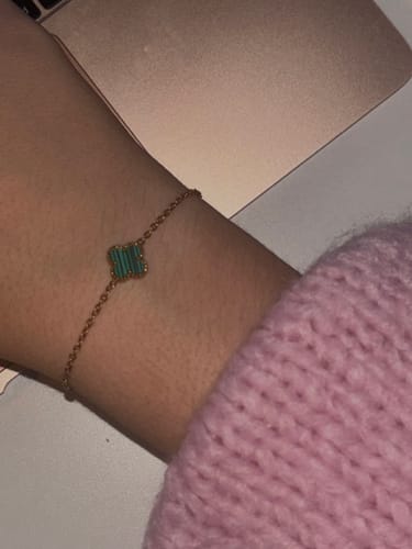 Kundin zeigt ihr Überraschungsgeschenk, ein vergoldetes Armband mit einem grünen Anhänger, an ihrem Handgelenk.