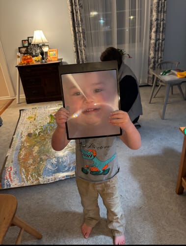 Customer's photo of a child holding the Magnifying Sheet, making their face look large and happy.