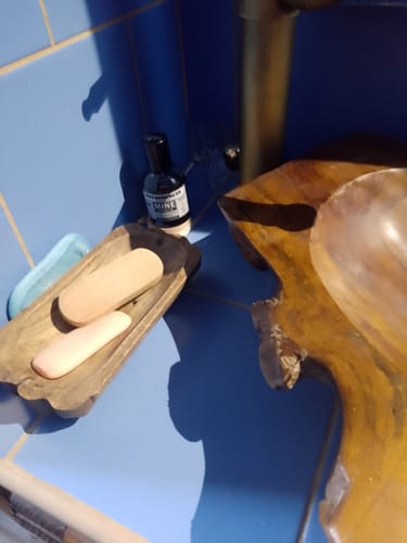 Il profumo GOODMORNING SIR di un cliente, posizionato su un mobile da bagno blu accanto a un lavabo in legno.