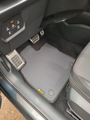 Klient pokazuje szary, dopasowany dywanik samochodowy po stronie kierowcy w samochodzie Cupra Formentor.