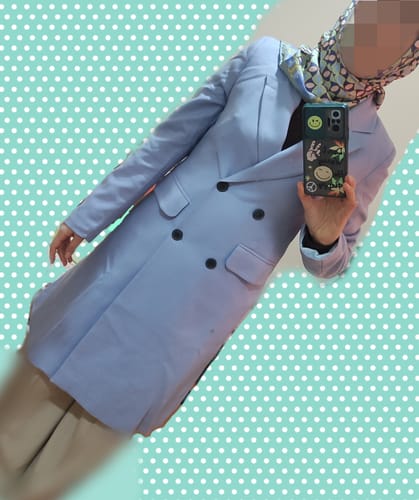 Yorumcu, üzerinde tam oturan yumuşak mavi poliviskon ceketi giyiyor.