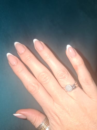 Customer's hand wearing the Everyday Elegance press-on nails, showing the classic almond-shaped, French manicure design.