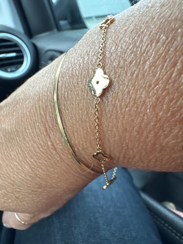 Customer's wrist showing the delicate gold Multi Clover Bracelet layered with a simple gold bracelet.