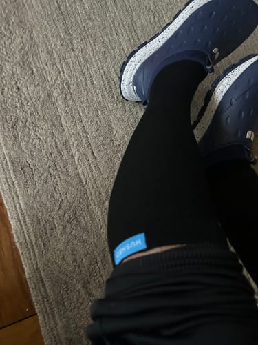 Customer wearing the black Performance Eucalyptus Compression Socks with shorts and blue shoes.