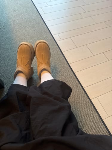 En kund bär vita Diasocks Stödstrumpor med svarta byxor och ljusbruna skor.