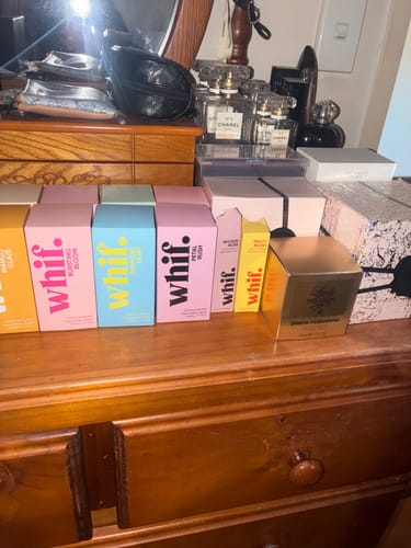 Customer's collection of perfumes on a dresser, including several colorful boxes from the same brand as Wicked Rose.