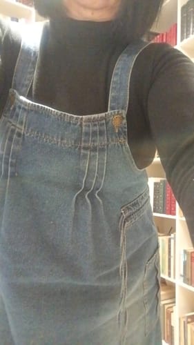 Reviewer wearing the black Half-Turtleneck Blouse layered under denim overalls indoors.