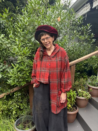 Reviewer standing outdoors wearing the red vintage plaid hooded shirt, styled open over dark pants.
