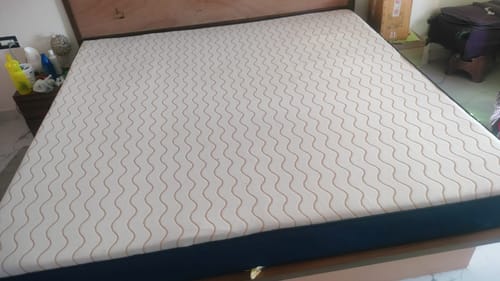 Customer's Flo Mattress Ergo with a patterned top and dark sides, placed on a wooden bed frame.