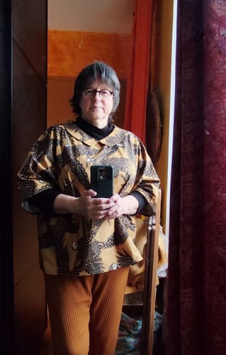 Cliente portant la Blouse Myriem à imprimé oiseaux, superposée sur un pull noir.