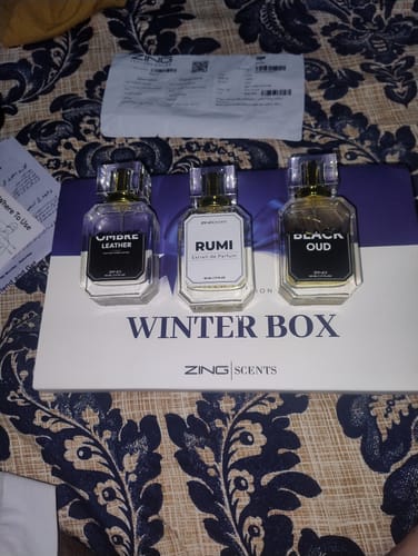 Customer's three perfume bottles from a fragrance set displayed on their white packaging box.