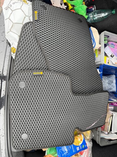 Recenzenta nowe, szare dywaniki samochodowe o fakturze rombów, leżące w bagażniku samochodu.