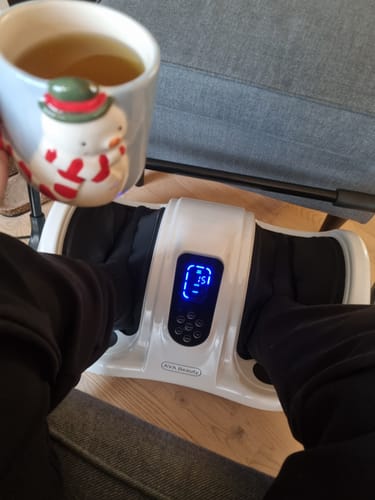 En anmelder slapper af med fødderne i det tændte fod- og lægmassageapparat, mens vedkommende holder en kop.
