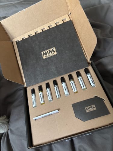 Recensore mostra il "Set campioni dolci e calde 2ml" aperto nella sua scatola, con le otto fiale di profumo allineate all'interno.