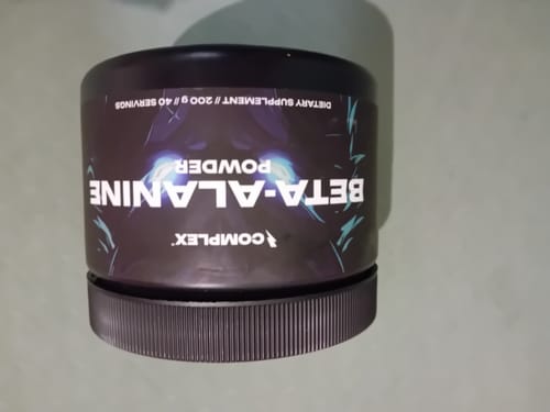 Customer's black tub of Complex Beta Alanine powder supplement sitting on a surface.