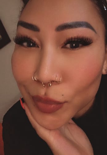Close-up of a reviewer wearing long, voluminous Siren lashes while resting her chin on her hand.