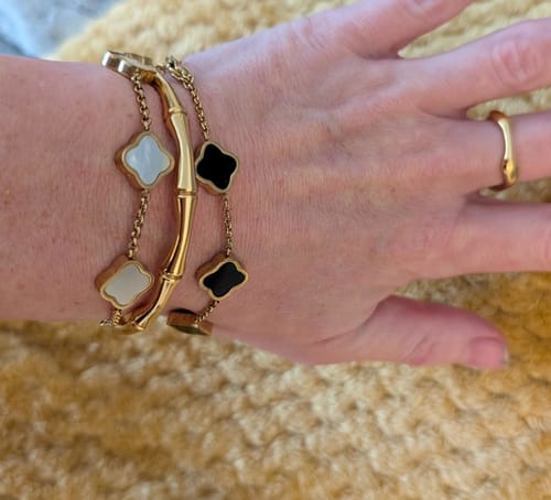 Customer wearing the gold Bamboo Cuff Bangle on their wrist, stacked between two other bracelets.