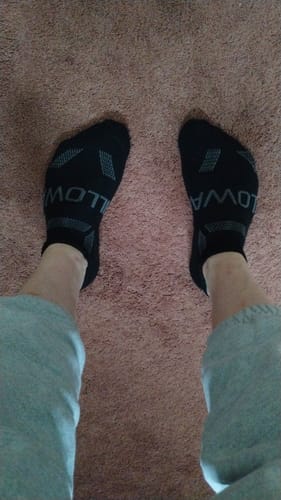 Reviewer's point-of-view shot wearing the black Men's Alpaca Socks on a carpet.