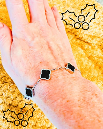 Customer wearing the Celine Silver Clover Bracelet with black enamel clover charms on their wrist.