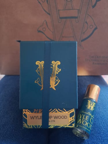 Customer's Wyle Cop Wood perfume bottle sitting next to its dark teal and gold packaging.