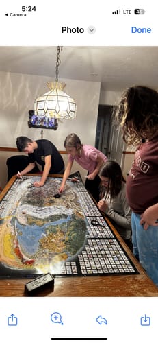 Customer's family gathered around a table, playing with the large World's Greatest Search & Discover poster.