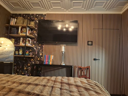 Customer's bedroom with Premium Acoustic Slatted Wall Panels installed as a feature wall behind a television.