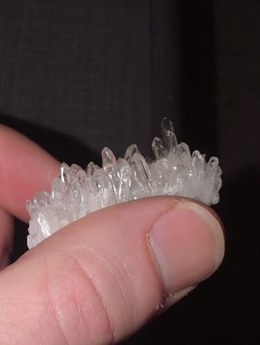 Close-up of a reviewer's hand holding a small, textured crystal cluster from the VIP Crystal Club.