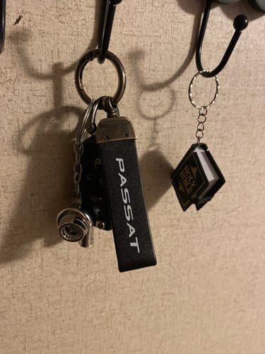Reviewer's silver TURBO KEYCHAIN attached to a keyring with other keys, hanging from a hook.