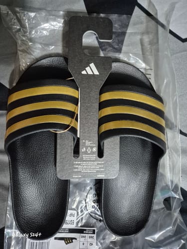 Customer's new black and gold adidas Adilette Aqua Slides shown in their original packaging with tags.