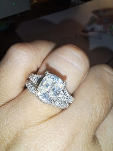 Close-up of a customer's hand wearing the sparkling Brooklyn split shank cushion ring.