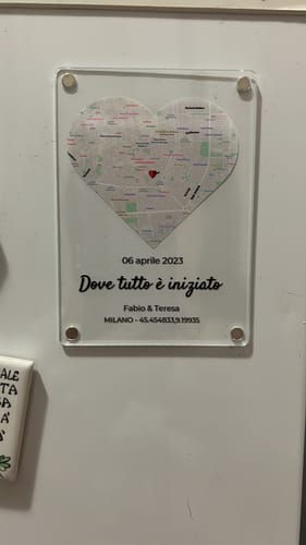 Rezensent zeigt den personalisierten Acrylmagneten „Wo alles begann“ mit einer herzförmigen Karte auf einer weißen Oberfläche.