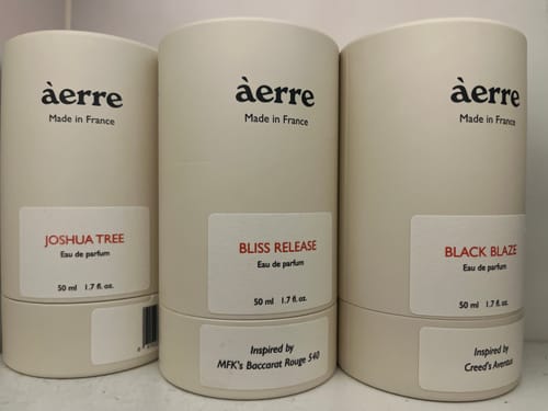Reviewer's Bliss Release perfume in its white cylindrical packaging, sitting next to two other similar fragrances from àerre.