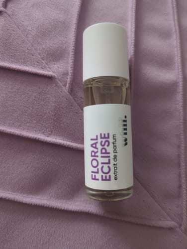 Customer's bottle of Floral Eclipse perfume resting on a textured purple fabric.