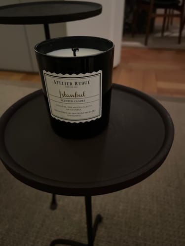 Recensent toont de onstoken Istanbul Geurkaars in de zwarte pot op een bijzettafeltje.