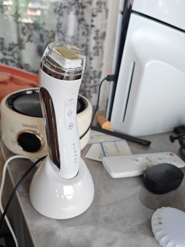 Customer's white and silver VEAUTY Dot & Aqualis Activator device sitting in its charging base on a desk.
