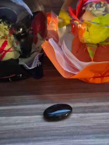 Customer's smooth, dark monthly crystal reflecting a blue light on a wooden surface.